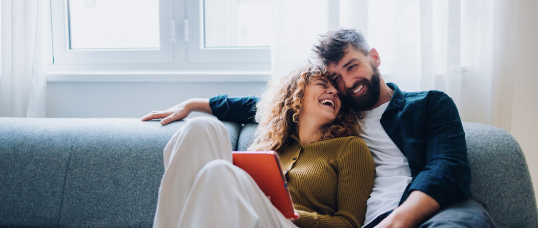 Couple embracing on couch with tablet