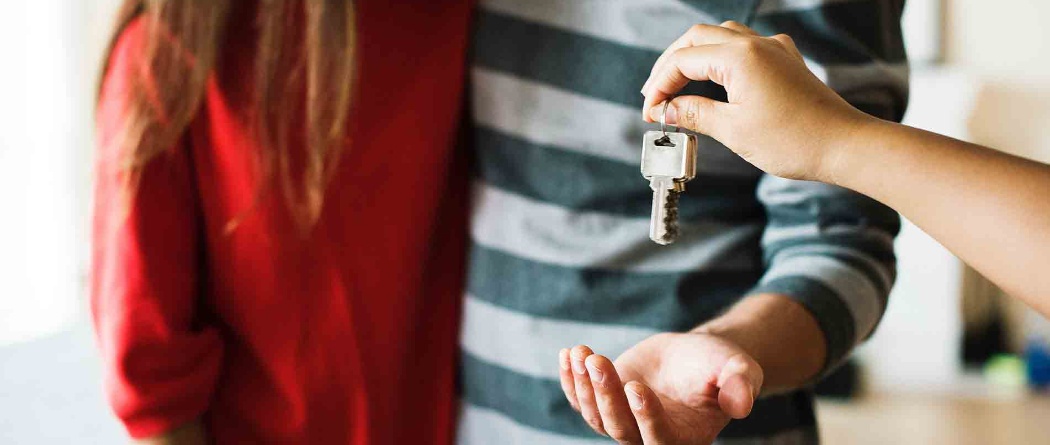 a person handing home keys to a couple
