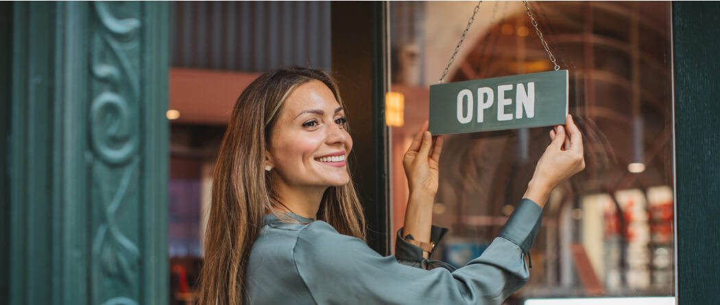 Business woman turning "open" sign in window
